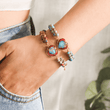 Load image into Gallery viewer, A photo of the red and light blue Jasper Heart Bracelet on the wrist with the model&#39;s hand casually resting inside the pants&#39; pocket
