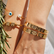 Load image into Gallery viewer, A model wearing Gold Bangle Evil Eye Black Stones and other Evil Eye bracelets
