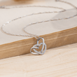 Load image into Gallery viewer, To My Daughter, Our Hearts Are Always Linked Together Interlocking Heart Necklace leaning on the edge of an open book
