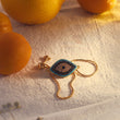 Load image into Gallery viewer, Ancient Protector Evil Eye Gold Tone Bracelet with oranges in the background
