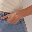 Load image into Gallery viewer, White Cross Bracelet worn by a model on her left wrist
