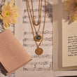 Load image into Gallery viewer, Multi-layered Star of David Emerald Necklace on placed top of a music sheet
