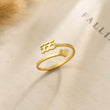 Load image into Gallery viewer, 555 Angel number gold ring placed on top of a piece of paper
