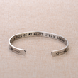 Load image into Gallery viewer, Silver plated memorial bracelet with engraved message &quot;A piece of my heart lives in heaven&quot; placed on top of brown fabric
