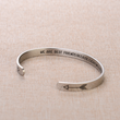 Load image into Gallery viewer, Motivational message printed in a silver plated cuff bracelet placed on top a brown fabric 
