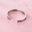 Load image into Gallery viewer, &quot;Not sisters by blood but sisters by heart&quot; engraved in a bracelet placed on top of a pink fabric
