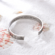 Load image into Gallery viewer, motivational message &quot;Not sisters by blood but sisters by heart&quot; engraved in a bracelet placed on top of sand
