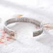 Load image into Gallery viewer, Silver cuff bracelet with &quot;I love you&quot; message placed over a pile of sand
