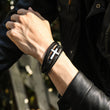 Load image into Gallery viewer, Silver cross leather bracelet for him, being worn by a model with a leather jacket
