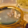 Load image into Gallery viewer, White Pearl Butterfly Earrings Studs placed on top of a magnifying glass
