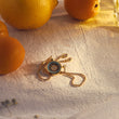 Load image into Gallery viewer, Round Illusion Evil Eye Gold Bracelet with oranges in the background
