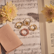 Load image into Gallery viewer, Turquoise Stones Hamsa Hand Ring and other rings on top of a music sheet
