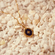 Load image into Gallery viewer, Oval Star of David Black Gold Necklace placed on top of small white stones
