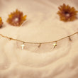 Load image into Gallery viewer, Cross Gold Ankle Bracelet placed on top of a cotton fabric together with dried sunflowers
