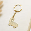 Load image into Gallery viewer, Gold dog Personalized Pet Sketch Keychain on the top of a book
