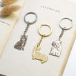 Load image into Gallery viewer, Personalized Pet Sketch Keychains on a page of an open book
