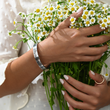 Load image into Gallery viewer, A model wearing You Are My Sunshine Silver Bangle while holding flowers
