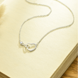 Load image into Gallery viewer, Infinite Heart Necklace place on a blank page of an open bookj
