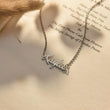 Load image into Gallery viewer, Silver Custom Fairy Name Necklace placed on a page of an open book
