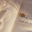 Load image into Gallery viewer, Crystal Evil Eye Medallion Necklace on a book page 
