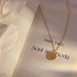 Load image into Gallery viewer, Round Evil Eye Gold Tone Necklace on top of a book page
