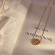 Load image into Gallery viewer, Evil Eye Talisman Necklace on top of a book page
