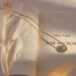 Load image into Gallery viewer, Evil Eye Medallion Gold Tone Necklace on top of a book page
