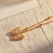 Load image into Gallery viewer, White Stone Butterfly Necklace Gold placed on top of a piece of fabric
